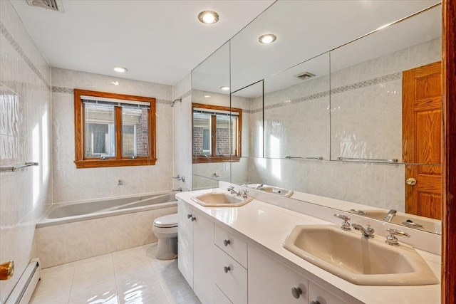 bathroom with a sink, a baseboard heating unit, tile walls, and visible vents