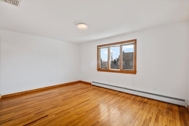 unfurnished room with baseboard heating, baseboards, light wood-type flooring, and visible vents