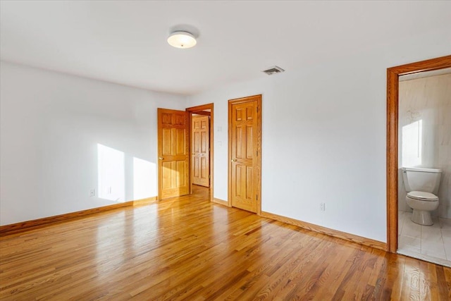 unfurnished bedroom featuring visible vents, baseboards, and wood finished floors