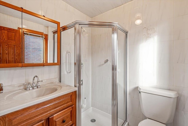 full bathroom with vanity, tile walls, toilet, and a stall shower