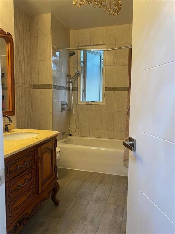 bathroom featuring vanity, wood finished floors, toilet, shower / tub combination, and a notable chandelier