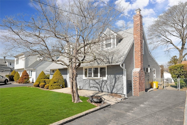 view of front of house with a gate, fence, driveway, a chimney, and a front lawn