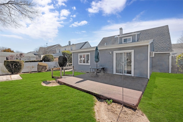 rear view of house featuring a patio area, a chimney, a yard, and fence