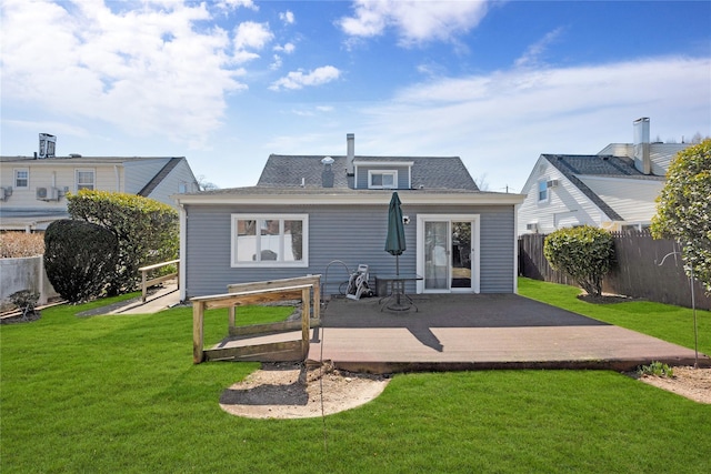 rear view of property with a deck, a yard, and fence