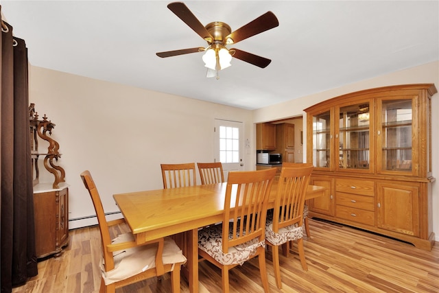 dining area with ceiling fan, a baseboard heating unit, and light wood-style floors