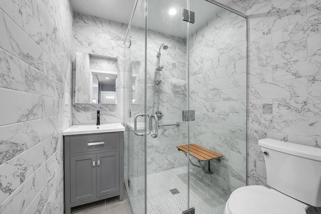 full bathroom featuring vanity, tile walls, toilet, and a shower stall