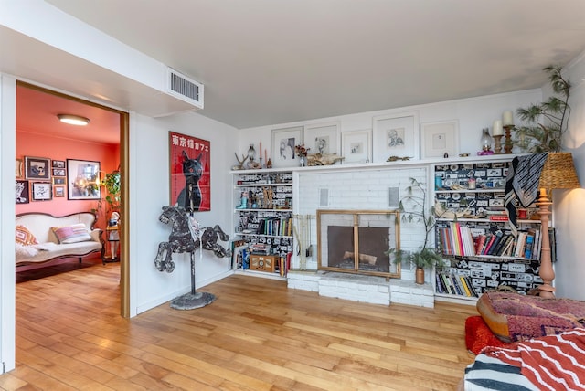 living area featuring visible vents, a brick fireplace, and wood finished floors