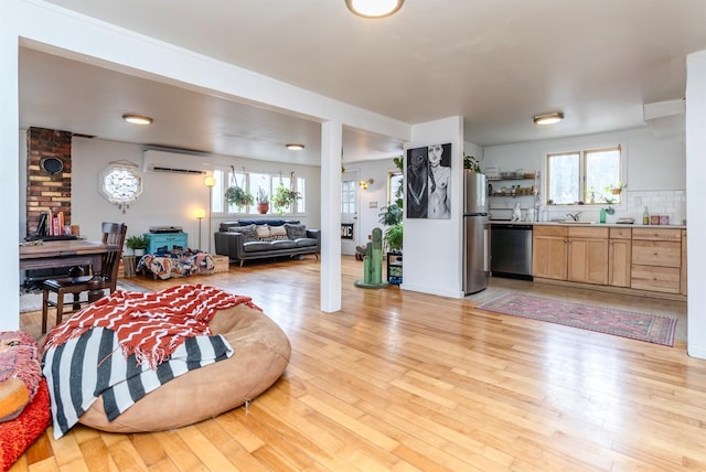 living room with a wall unit AC and light wood-style flooring