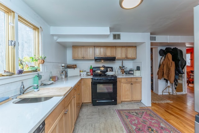 kitchen with visible vents, decorative backsplash, range hood, gas stove, and a sink