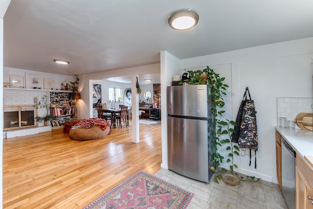 kitchen with light countertops, a fireplace, light wood-type flooring, and stainless steel appliances