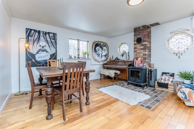 dining area with a healthy amount of sunlight, a wood stove, and wood finished floors