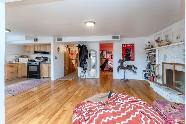 unfurnished living room with visible vents, light wood-style flooring, a fireplace, and stairway