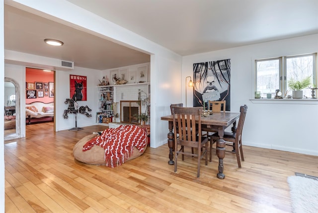 dining area with visible vents, a fireplace, baseboards, and wood finished floors