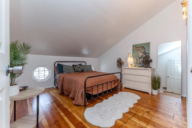 bedroom featuring baseboards, wood-type flooring, and vaulted ceiling