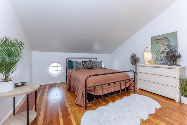 bedroom featuring hardwood / wood-style floors, vaulted ceiling, and baseboards