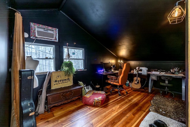 home office featuring hardwood / wood-style flooring, a wall unit AC, and vaulted ceiling