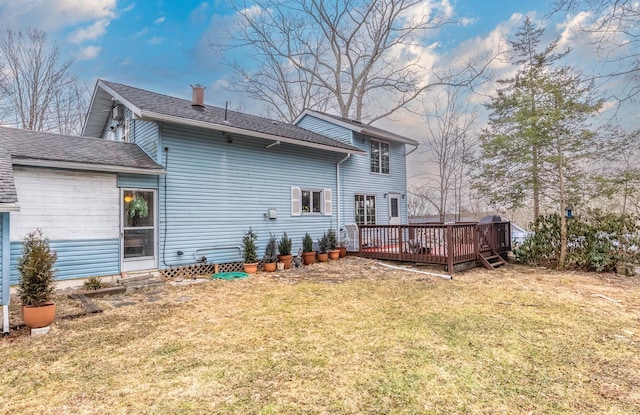 rear view of house featuring a deck, a lawn, and a shingled roof