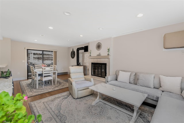 living room featuring a wall mounted air conditioner, wood finished floors, a high end fireplace, recessed lighting, and baseboards