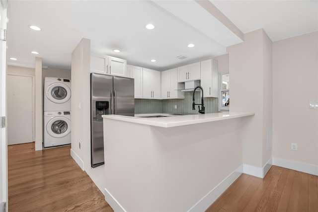 38 Marjorie Dr, Monticello, NY 12701 - kitchen with light wood-type flooring, stacked washer and dryer, decorative backsplash, a peninsula, and stainless steel fridge