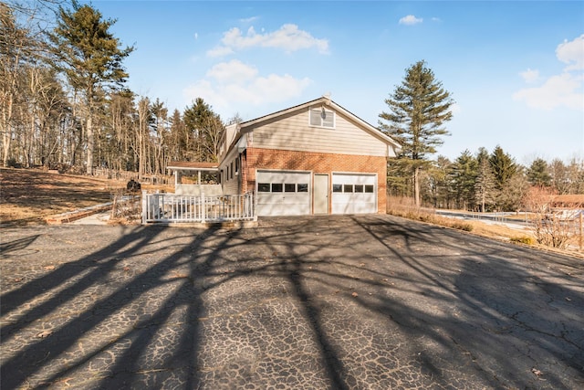 38 Marjorie Dr, Monticello, NY 12701 - view of property exterior featuring aphalt driveway, an attached garage, and brick siding