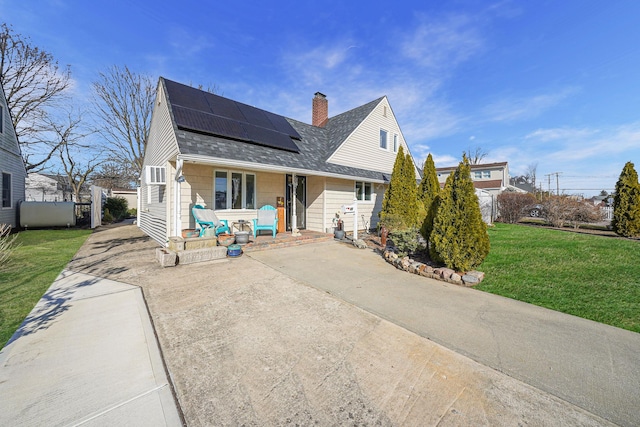 view of front of property featuring solar panels, a front lawn, fence, roof with shingles, and a chimney