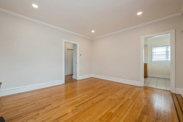 unfurnished room with crown molding, light wood-style flooring, and baseboards