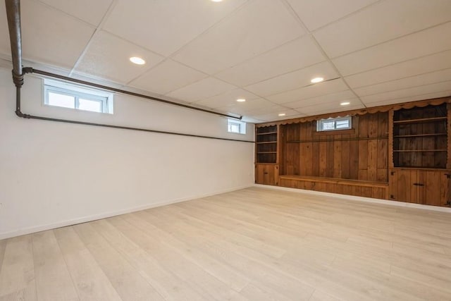 below grade area with wood finished floors, baseboards, recessed lighting, a drop ceiling, and wood walls