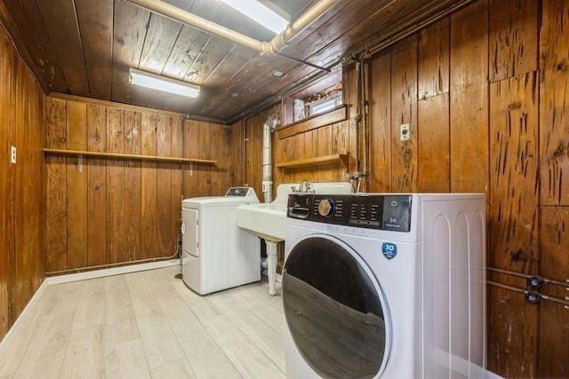 washroom with light wood finished floors, laundry area, wood ceiling, wood walls, and washer and dryer