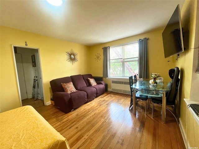 living area featuring baseboards, wood-type flooring, and radiator heating unit