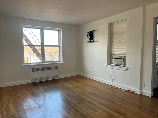 empty room featuring radiator heating unit, dark wood-style floors, baseboards, and cooling unit