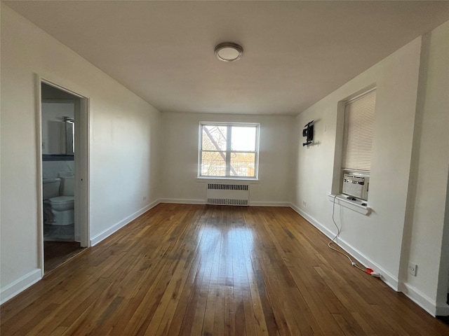 unfurnished room with baseboards, radiator heating unit, and dark wood-type flooring