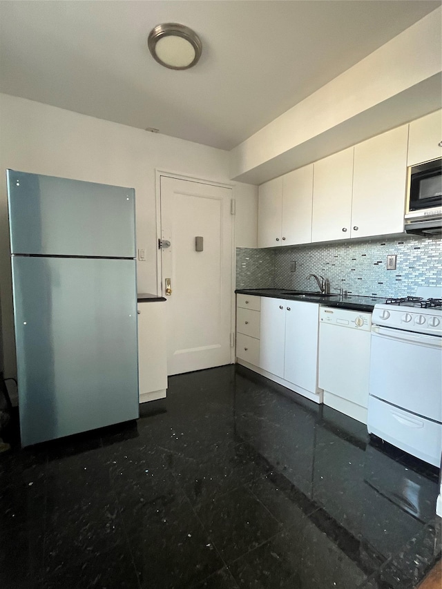 kitchen with white appliances, a sink, white cabinets, dark countertops, and tasteful backsplash
