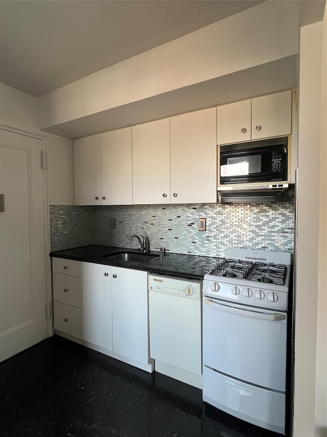 kitchen with dark countertops, decorative backsplash, white appliances, white cabinetry, and a sink