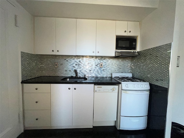 kitchen featuring dark countertops, backsplash, white appliances, and a sink