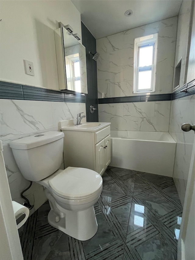 bathroom featuring vanity, tile walls, toilet, marble finish floor, and shower / bathtub combination