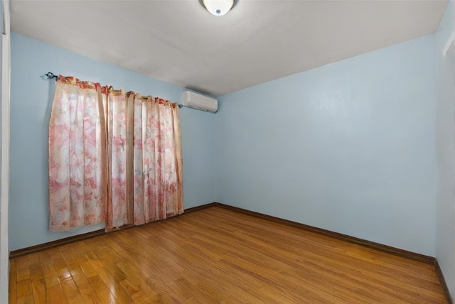 empty room with baseboards, wood finished floors, and a wall mounted AC