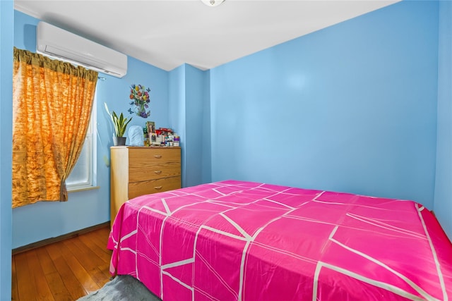 bedroom featuring hardwood / wood-style flooring, baseboards, and a wall mounted air conditioner