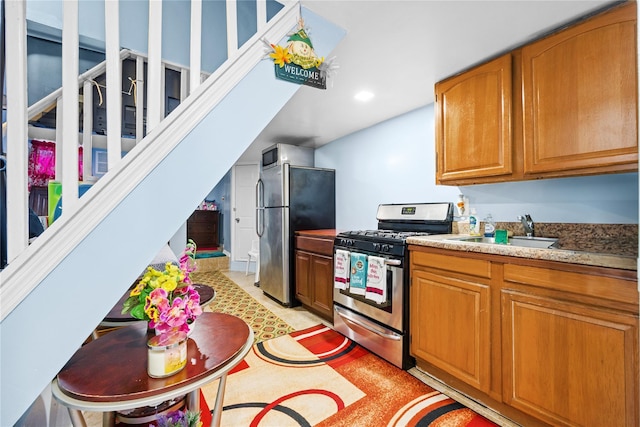 kitchen featuring a sink, stainless steel appliances, brown cabinets, and light countertops