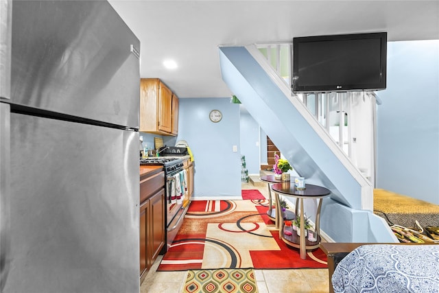 kitchen featuring light tile patterned flooring, brown cabinetry, baseboards, and appliances with stainless steel finishes