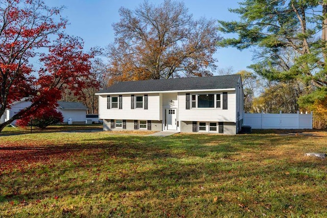 raised ranch featuring a front lawn and fence