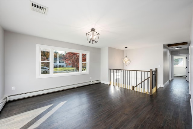 unfurnished room with visible vents, dark wood-type flooring, a notable chandelier, a baseboard heating unit, and baseboard heating