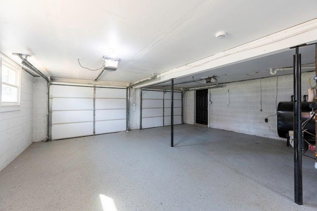 garage with concrete block wall, a garage door opener, and heating fuel