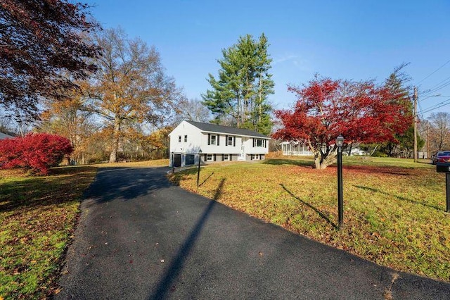 raised ranch featuring a front lawn and aphalt driveway