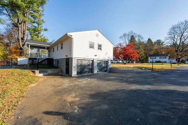 view of side of property featuring aphalt driveway and a garage