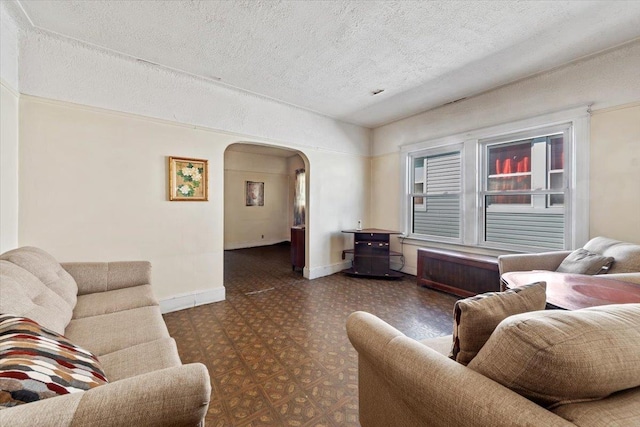 living room with arched walkways, tile patterned floors, a textured ceiling, and baseboards