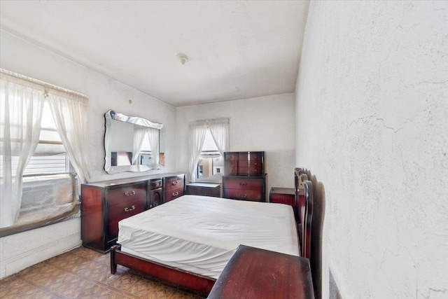 bedroom featuring tile patterned floors and a textured wall