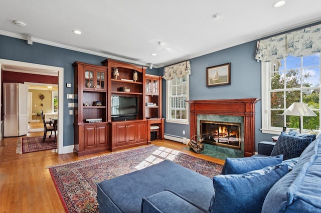 living room featuring baseboards, light wood-style flooring, a fireplace, a baseboard heating unit, and crown molding