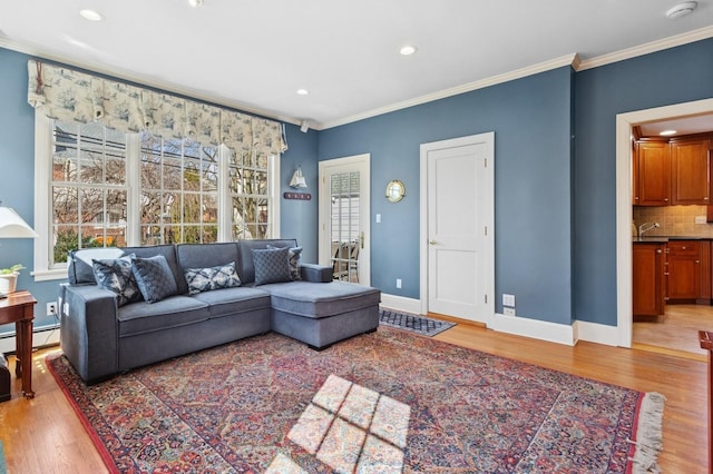 living room with baseboards, recessed lighting, ornamental molding, a baseboard heating unit, and light wood-type flooring