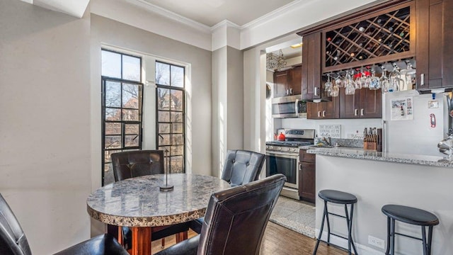 dining room featuring dark wood finished floors, a dry bar, and ornamental molding