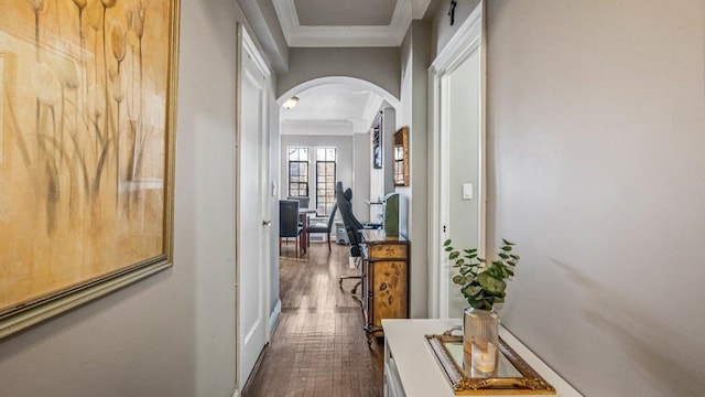 hall featuring arched walkways, crown molding, and wood finished floors